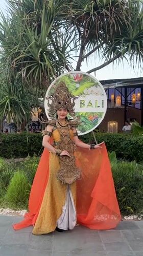 Woman poses in traditional Balinese costume at Denpasar sign