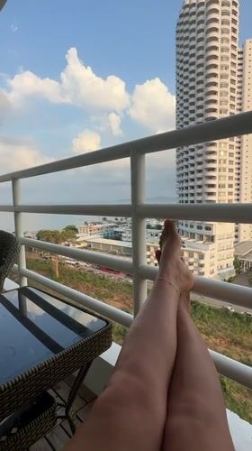 Person relaxes on balcony railing in Pattaya Thailand