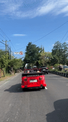 Red convertible drives through morning traffic in Denpasar, Indonesia