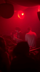 DJs perform in red-lit nightclub during early morning hours