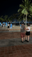 Couples dance on Đà Nẵng beach promenade at night