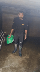 Man handles water containers in flooded concrete structure