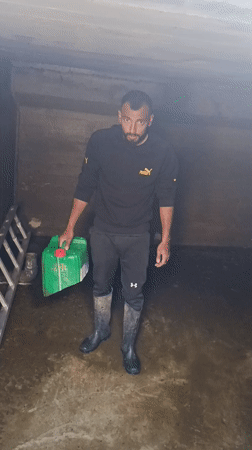 Man handles water containers in flooded concrete structure