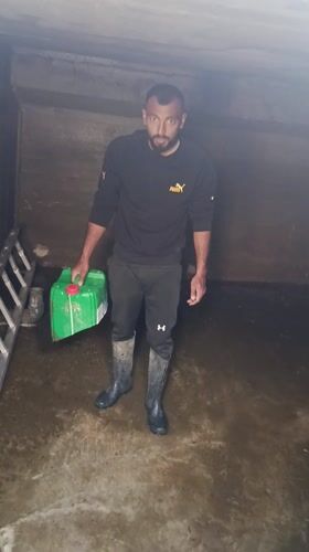 Man handles water containers in flooded concrete structure