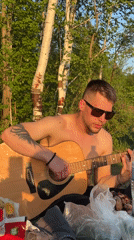 Man plays guitar during lakeside barbecue gathering
