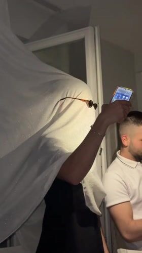 Person in white cloth holds smartphone indoors in Kalofer
