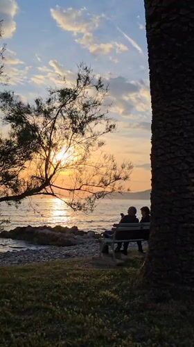 Couple watches golden sunset from bench in Bar, Montenegro