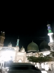 Illuminated mosque with green domes captured at night
