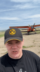 Group gathers around vintage biplane at Russian airfield