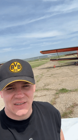 Group gathers around vintage biplane at Russian airfield