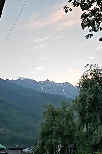 Rooftop musical performance amid scenic Himalayan mountain views in Vashisht