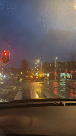Driver waits at red light during rainy evening