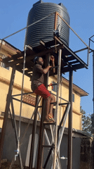 Worker performs electrical maintenance on urban water tower structure
