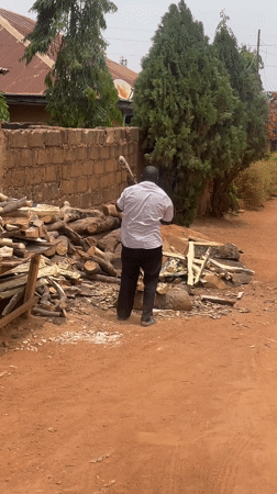 Man chops wood outdoors in Jos, Nigeria