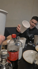 Young men toast drinks at table gathering
