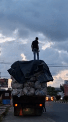 Man stands atop loaded truck in Lhokseumawe