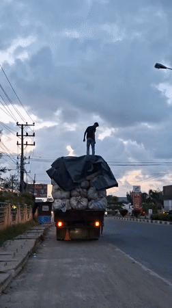 Man stands atop loaded truck in Lhokseumawe