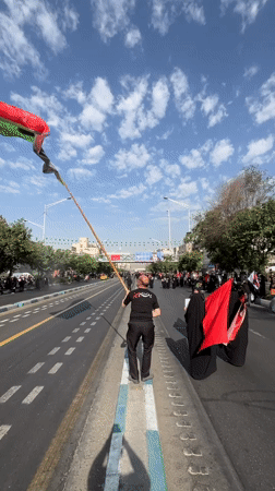 Iranian flag raised roadside as crowd gathers in Tehran