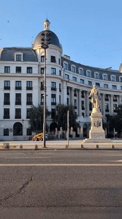 Stone statue outside grand domed building in Bucharest