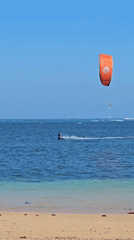 Kitesurfing off Denpasar coast with boats nearby