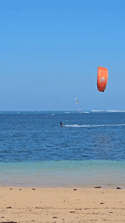 Kitesurfing off Denpasar coast with boats nearby