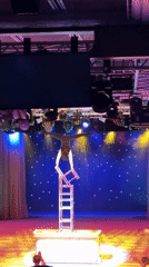 Performer executes handstand on four-chair stack during late-night act