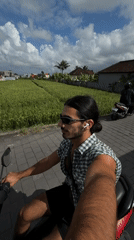 Man rides scooter past rice paddies in North Kuta
