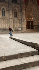 Skateboarder practices tricks near Barcelona Cathedral during evening session