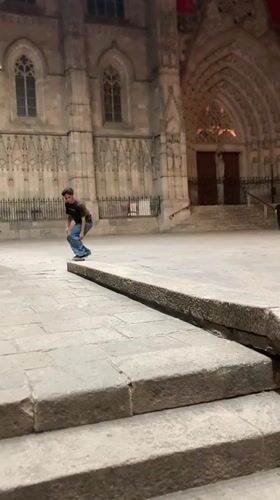 Skateboarder practices tricks near Barcelona Cathedral during evening session