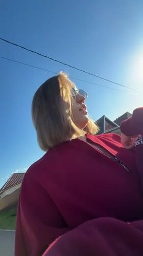 Woman applies makeup outdoors in Reshetnikovo spring afternoon