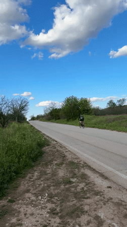 Cyclist travels rural road under cloudy skies in Perushtitsa