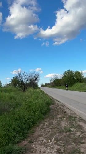 Cyclist travels rural road under cloudy skies in Perushtitsa