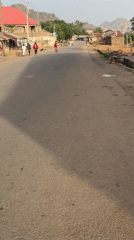 Morning pedestrians walk along quiet street in Bukuru, Nigeria