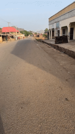 Morning pedestrians walk along quiet street in Bukuru, Nigeria