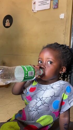 Girl drinks water from bottle in Kuru Dungus Nigeria