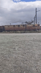 Brown train 032 crosses tracks observed from parked vehicle