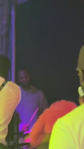 Here's a description of the video:

The video is shot inside a crowded nightclub, with the focus on a group of people standing near the DJ booth. The club is dimly lit, with various colored lights flashing.

The people in the scene are mostly young men, dressed in casual clothing. Several are looking at their phones. Some are conversing.

In the background, a sign reads "CLUB 07." The DJ booth has a laptop on it. The overall atmosphere suggests a lively, social environment.