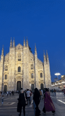 Milan Cathedral illuminated at dusk draws evening crowds