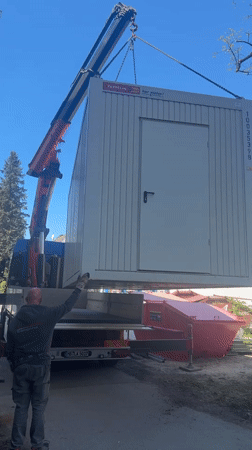Crane truck lifts white cabin in Munich