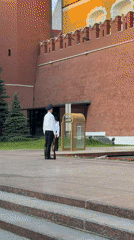 Two armed guards in uniform stand at brick wall