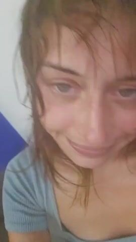A woman is filmed from a close-up perspective as she moves her head and touches her face. The video then shows a wide shot of the woman sitting on a couch with a gray blanket. Finally, the video shows a close-up of blue and white striped fabric.