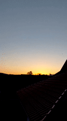 Urban sunset documented with gradient sky and jet contrails