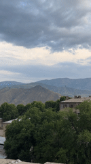 Cloudy afternoon over a mountain-backed city, storm rolling in