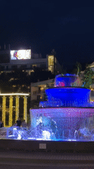 Street musician performs near illuminated fountains in Gelendzhik waterfront