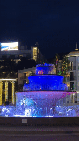 Street musician performs near illuminated fountains in Gelendzhik waterfront