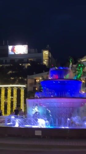 Street musician performs near illuminated fountains in Gelendzhik waterfront