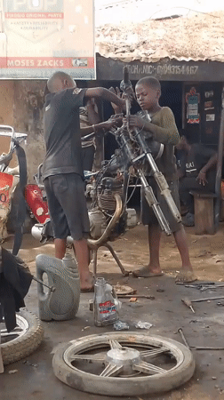 Young mechanics repair motorcycle at Nigerian garage
