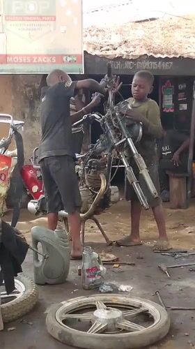 Young mechanics repair motorcycle at Nigerian garage