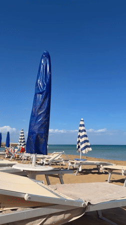 Beach scene captured in Noto, Italy with umbrellas and loungers