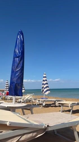 Beach scene captured in Noto, Italy with umbrellas and loungers